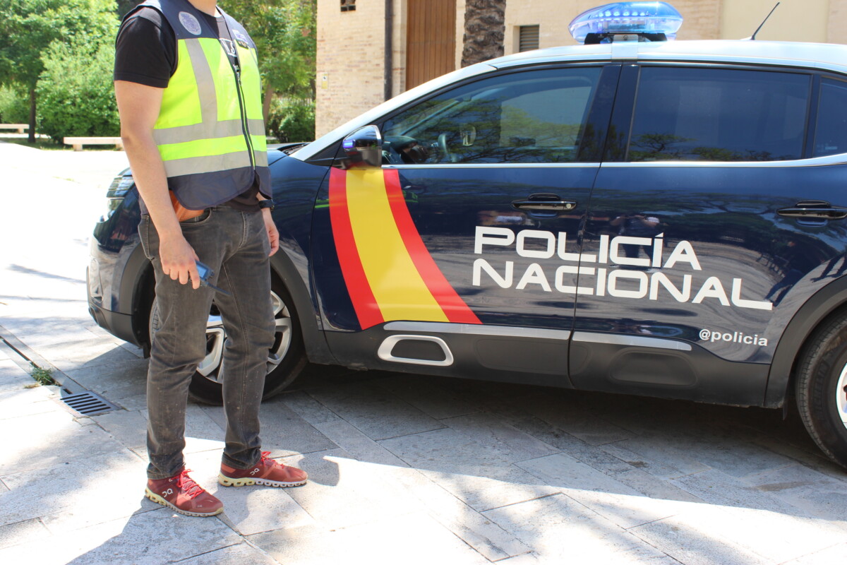 Un agente de la Policía Nacional junto al coche patrulla